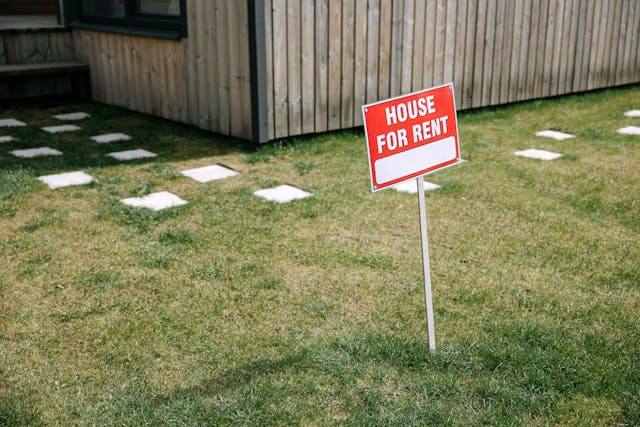 a “house for rent” sign on a green lawn